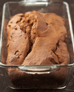 A loaf of deep golden Pumpkin Up Chai bread in a glass loaf pan.