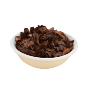 A small white bowl of roasted cacao shells, deep brown and fiberous.